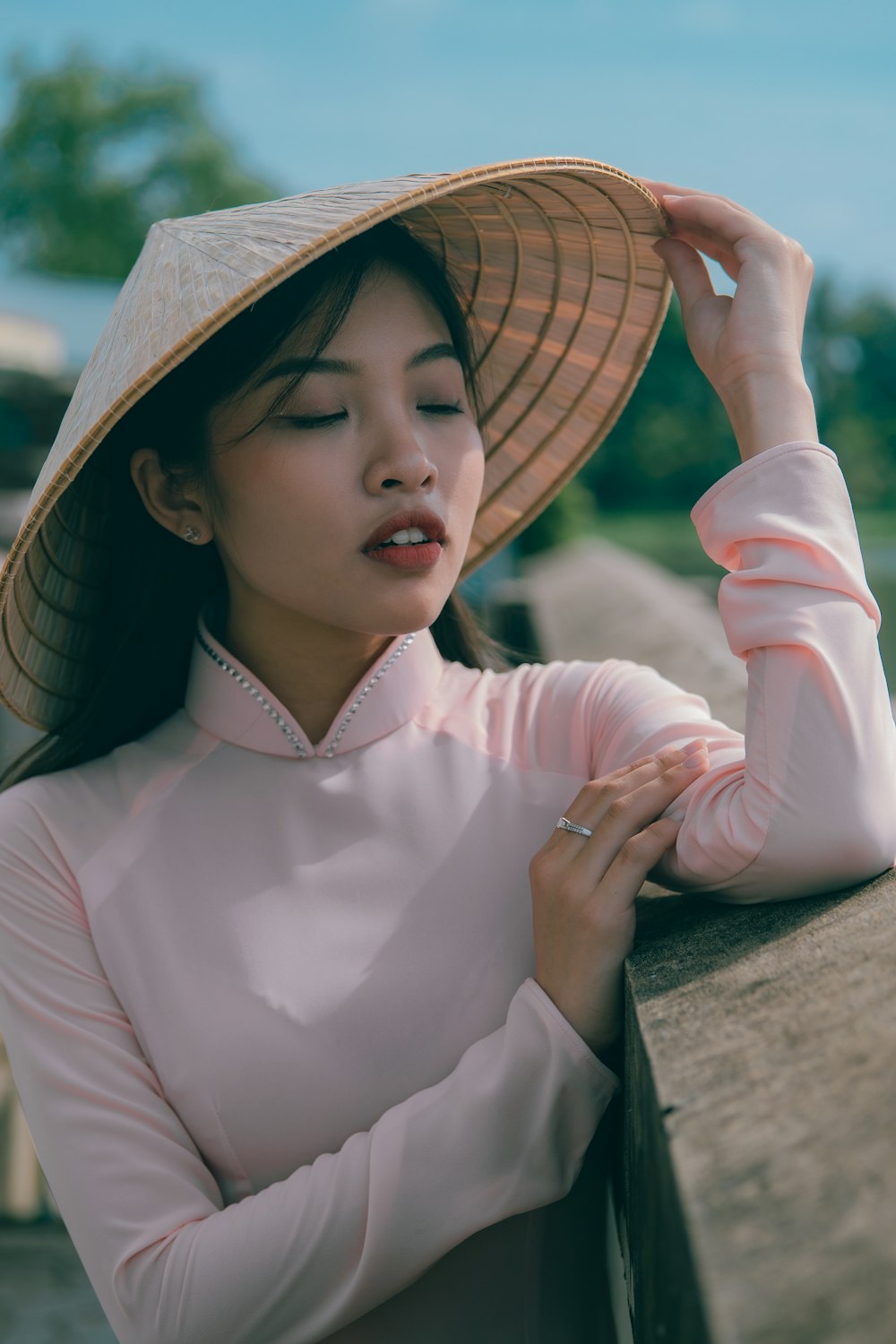 a woman wearing a hat leaning on a rail