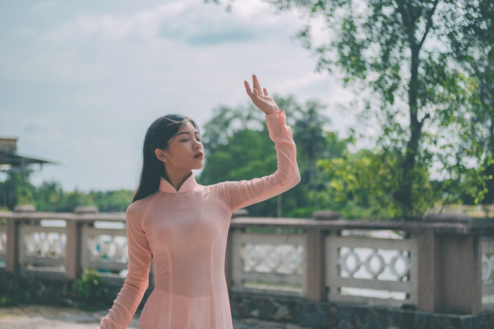 a woman in a pink dress is holding her hand up