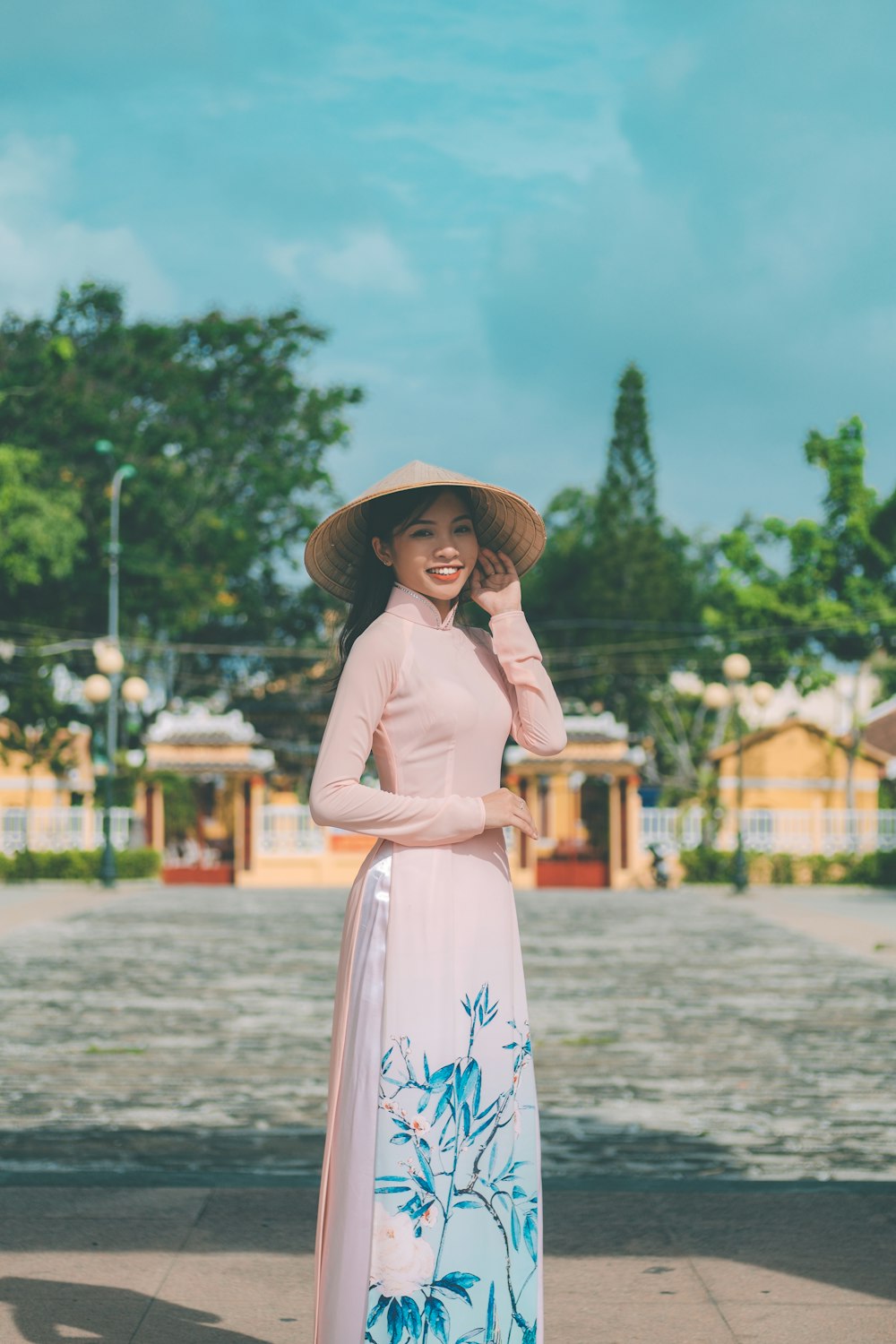 a woman in a long dress and hat posing for a picture