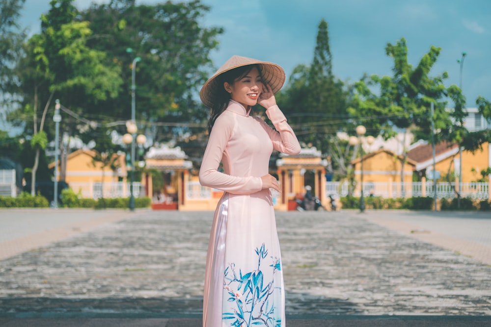 a woman in a pink dress and hat posing for a picture