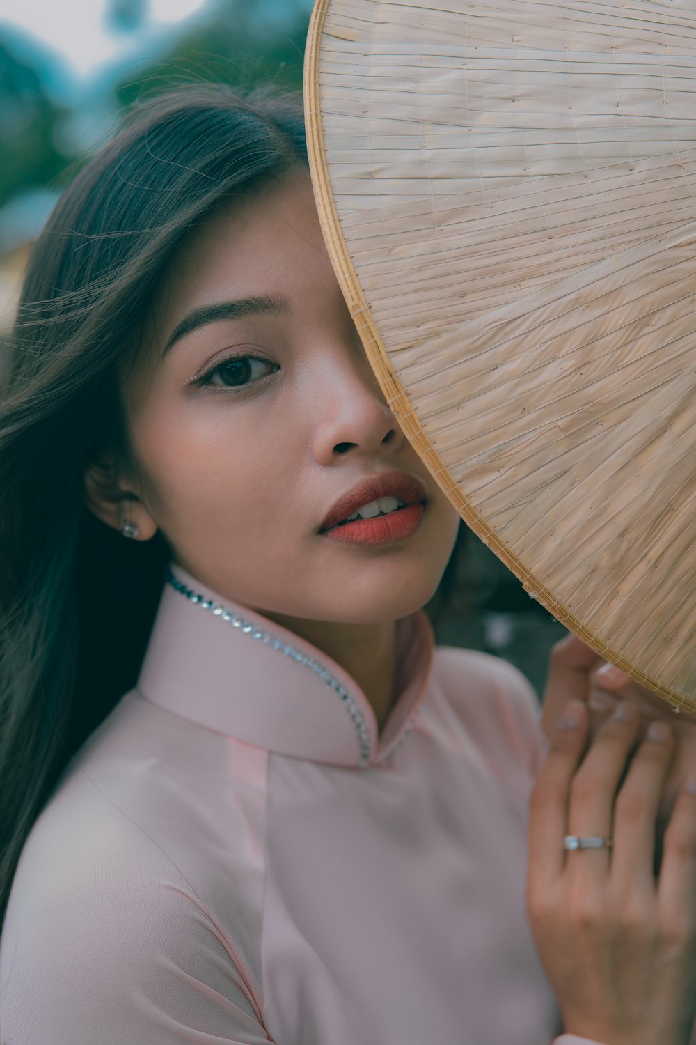 a woman holding a bamboo fan over her face