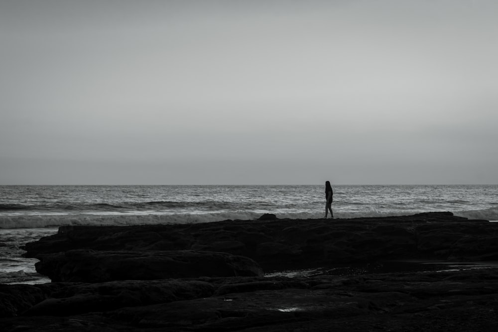 a person standing on a rocky beach next to the ocean