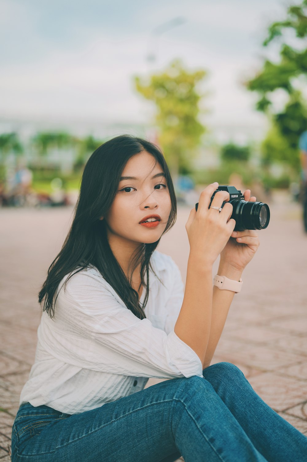 a woman sitting on the ground holding a camera