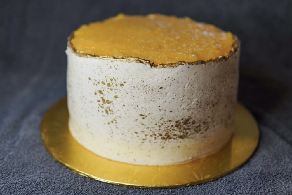 um bolo branco e dourado em uma placa de ouro