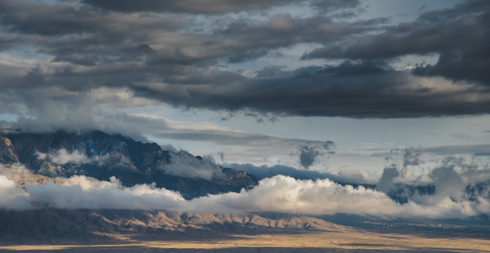 a large mountain covered in clouds under a cloudy sky