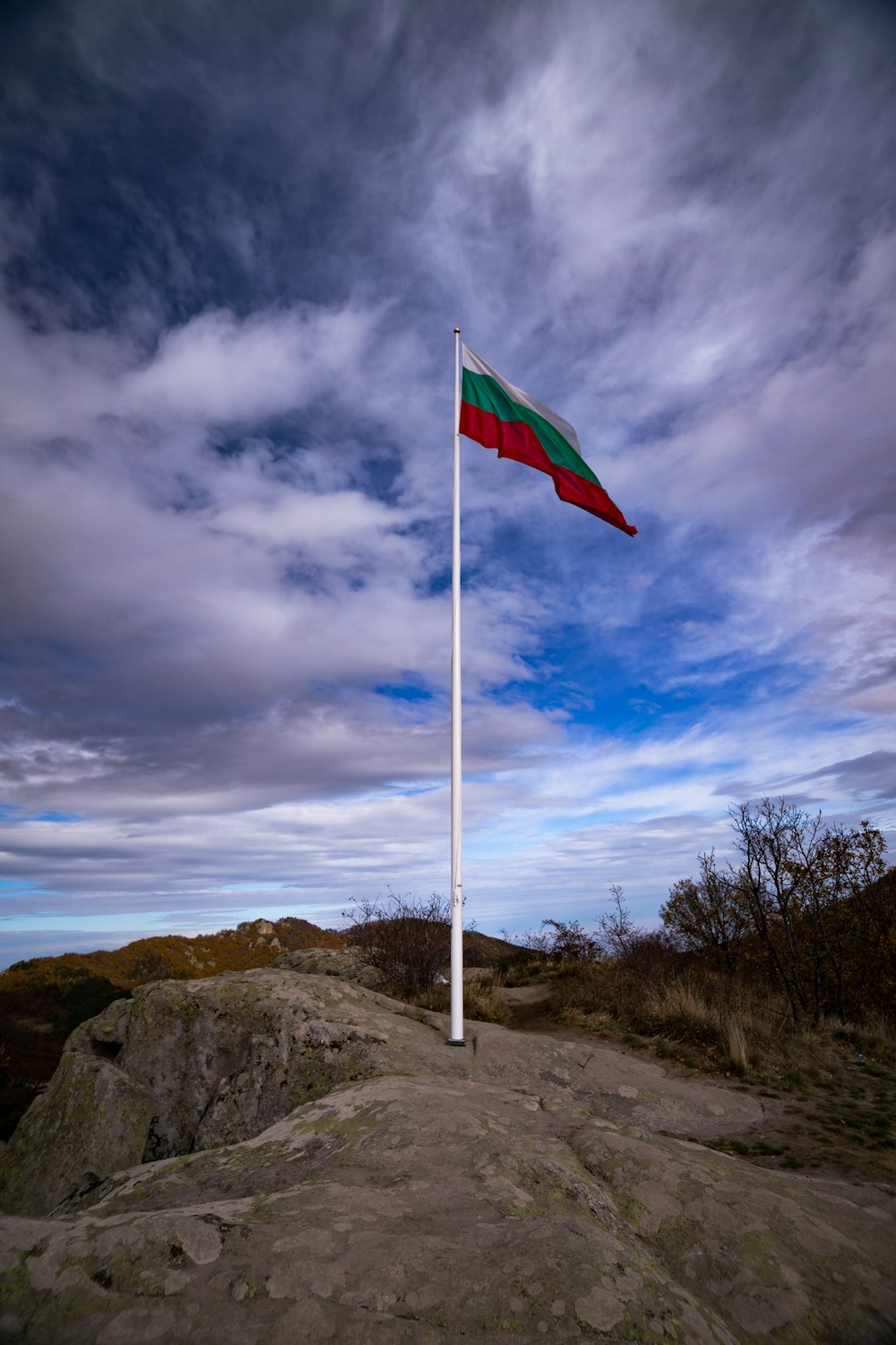 a flag on top of a rock with a sky background