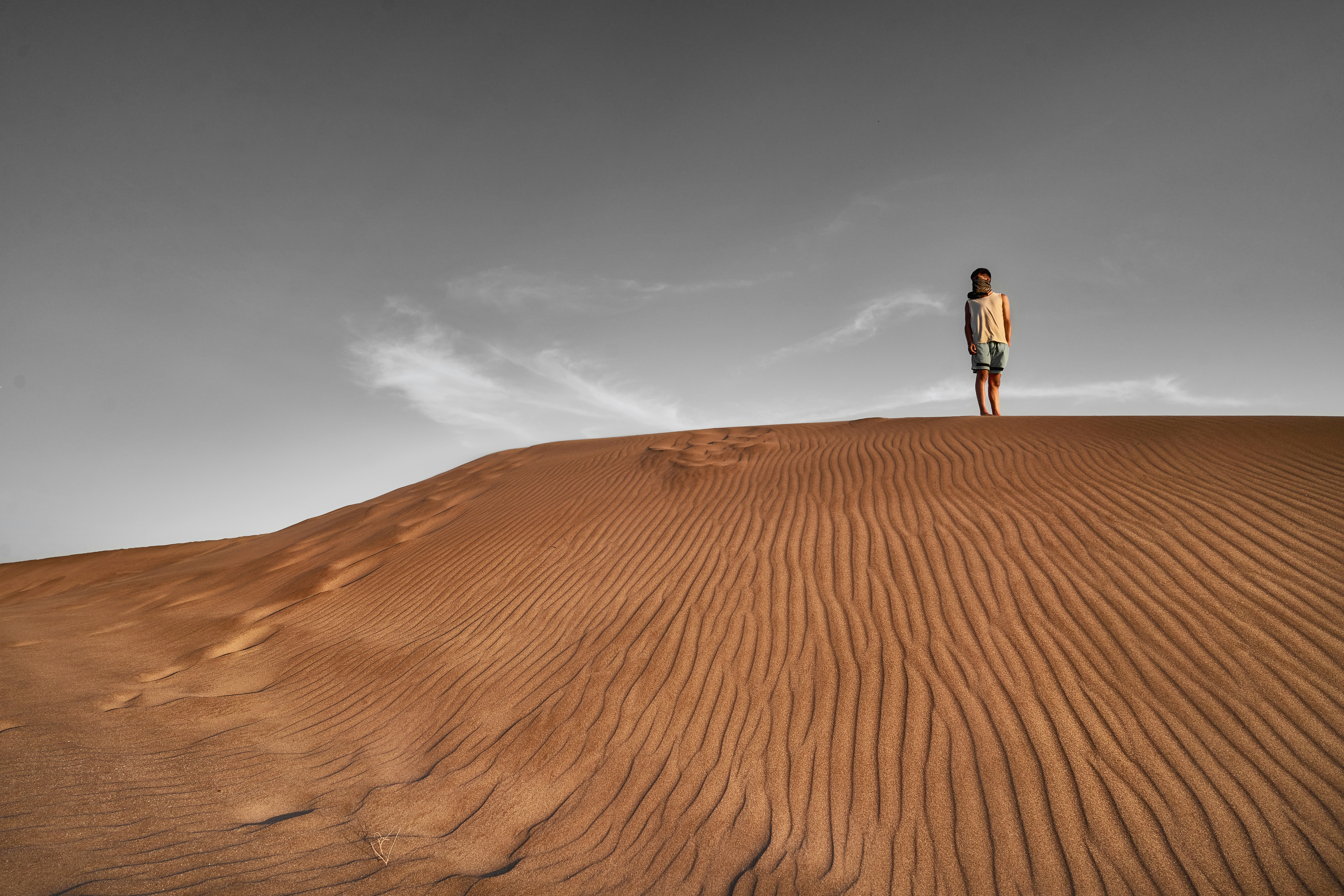 Un homme debout au sommet d’une dune de sable