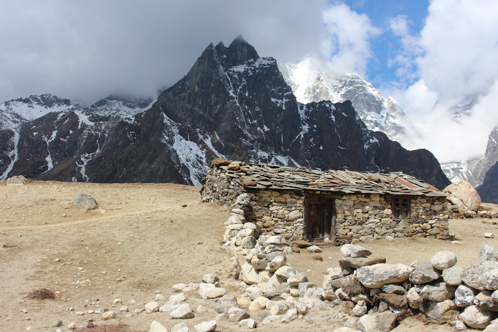 uma cabana de pedra com uma montanha no fundo