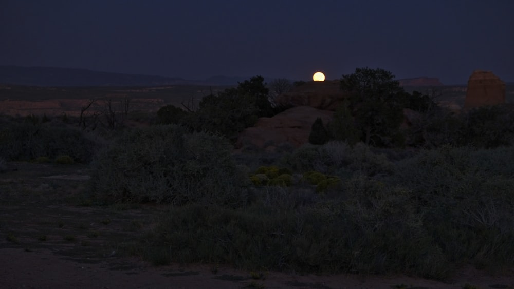 a full moon rises over a desert landscape