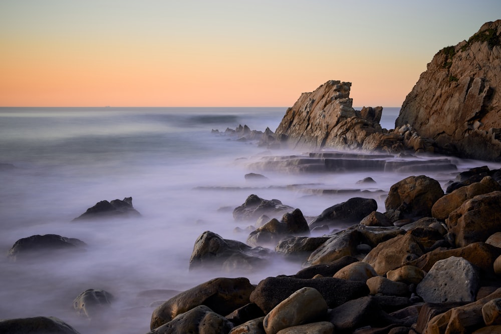 a long exposure of the ocean with rocks in the foreground