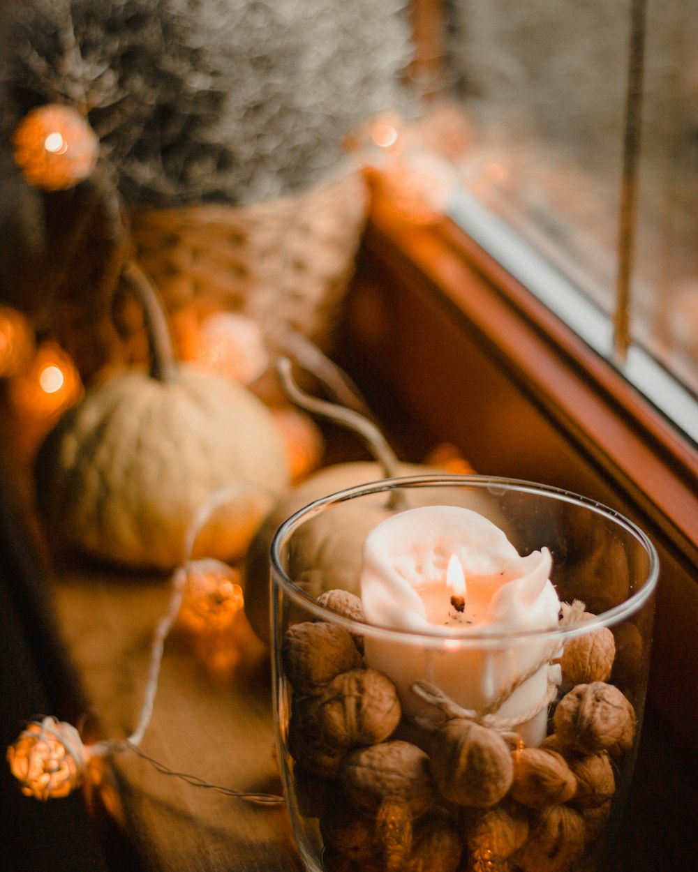 a glass filled with nuts next to a window