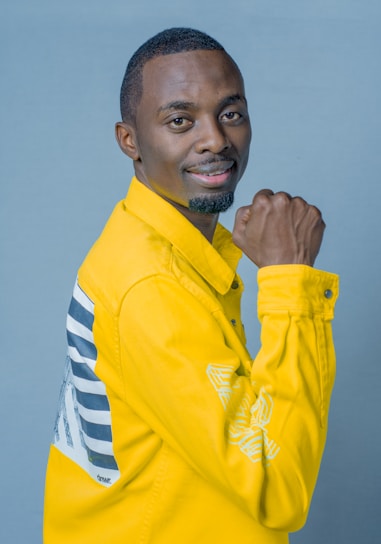 A cheerful model wearing a bright yellow jacket paired with colorful accessories against a city backdrop.