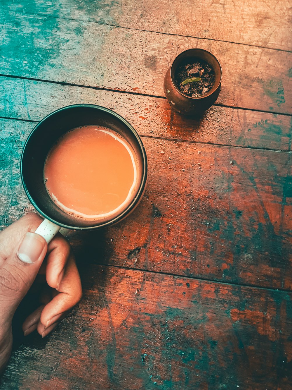 une personne tenant une tasse de thé sur une table en bois