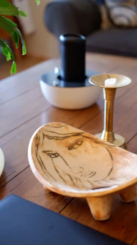 A sleek, modern decorative bowl resting on a minimalist wooden centre table.