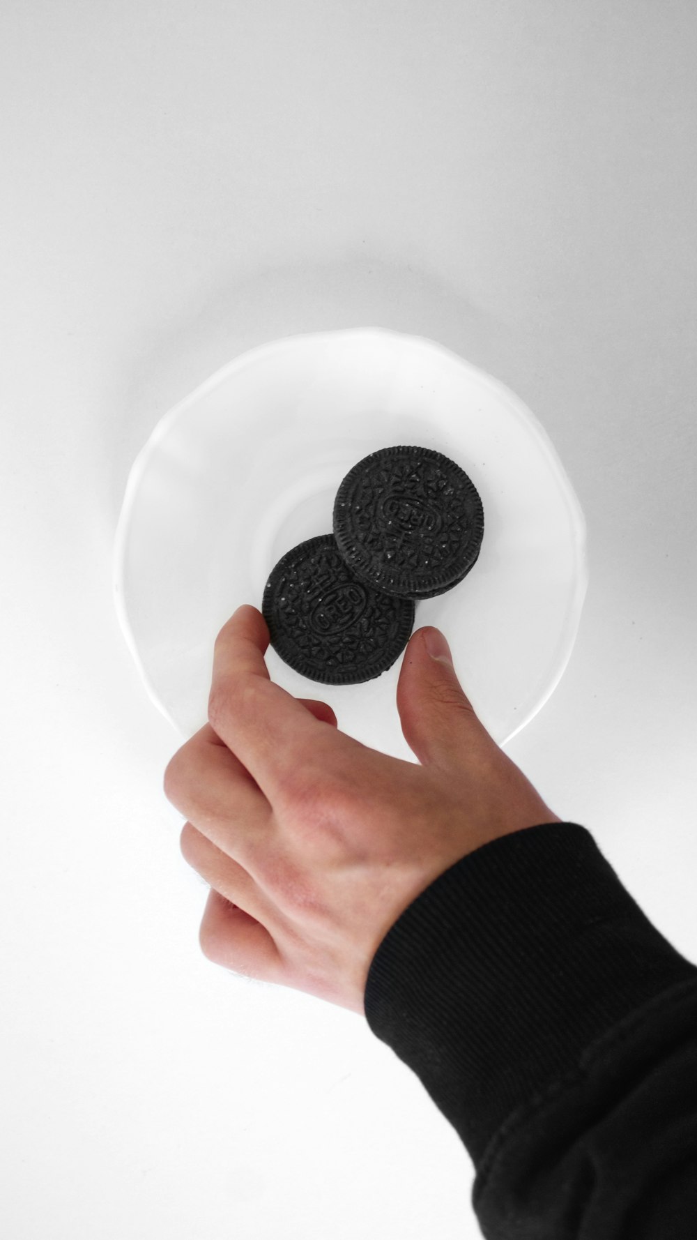 a person holding a plate with two cookies on it
