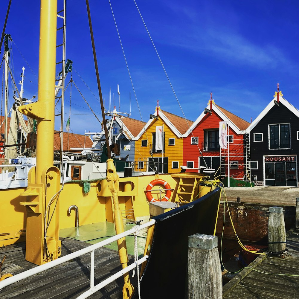 a yellow boat docked in front of a row of colorful houses