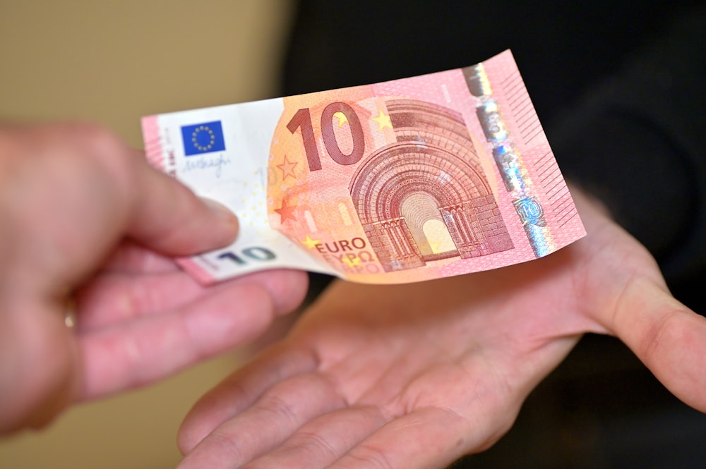 a person holding a ten euros bill in their hands