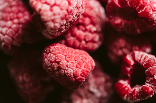 Close-up of vibrant frozen fruits glistening with frost, arranged artistically on a dark slate surface.