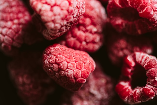 Close-up of frozen raspberries with frost on a rustic wooden surface