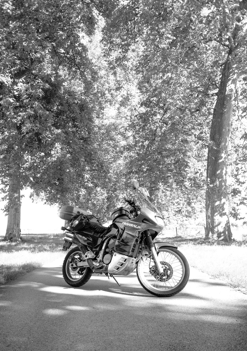 a black and white photo of a motorcycle parked on the side of the road