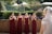 A group of smiling bridesmaids each carrying their monogrammed burlap tote bags at an outdoor wedding.