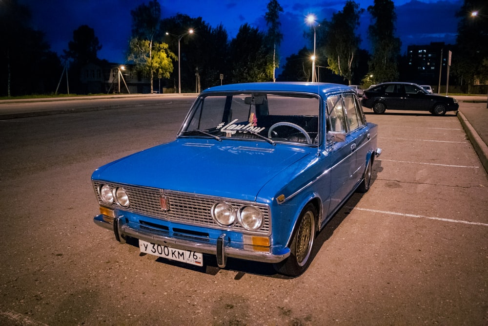 a blue car parked in a parking lot at night