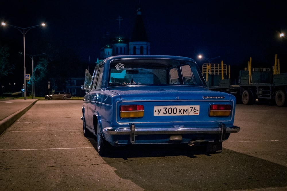 a blue car parked in a parking lot at night