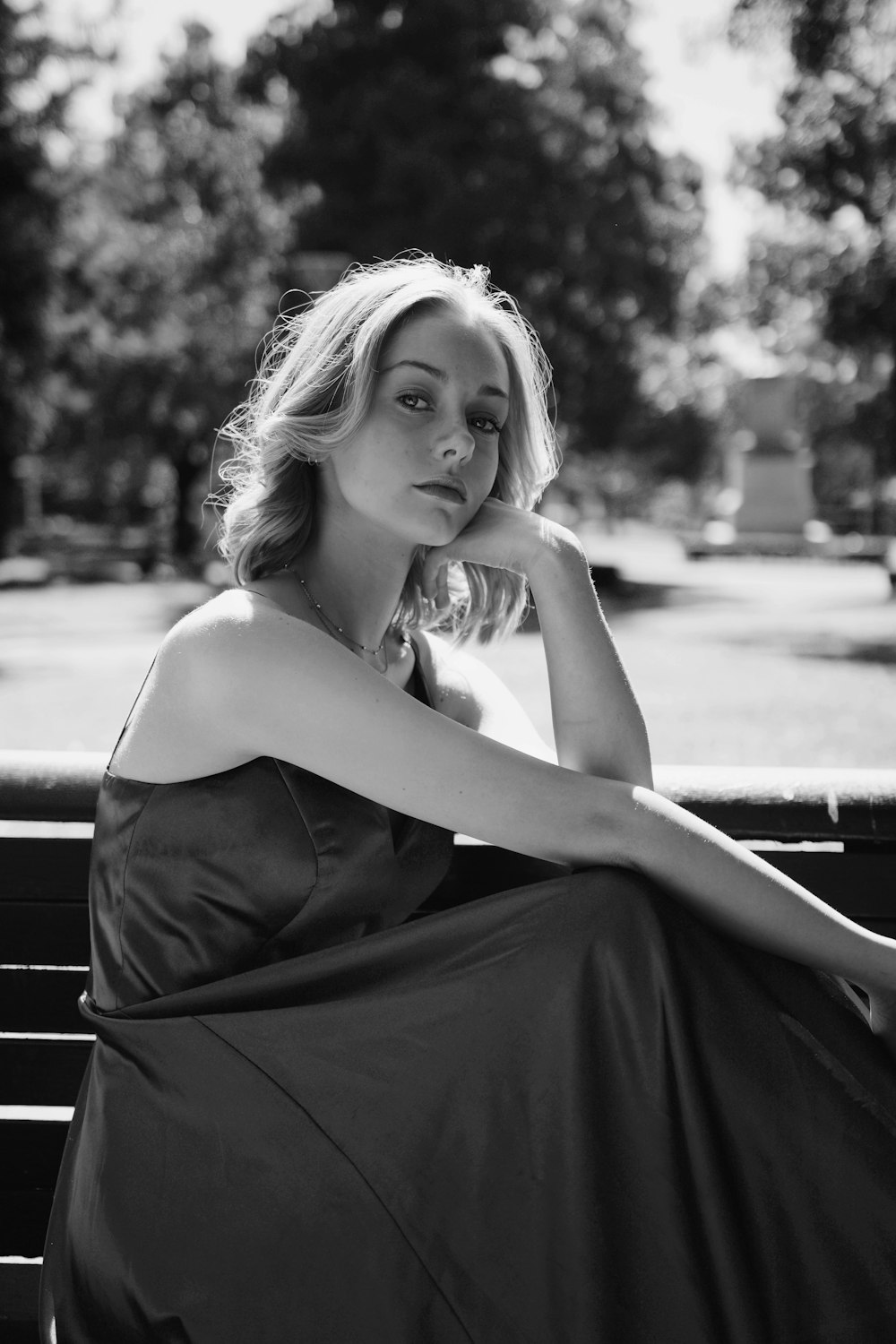 a black and white photo of a woman sitting on a bench