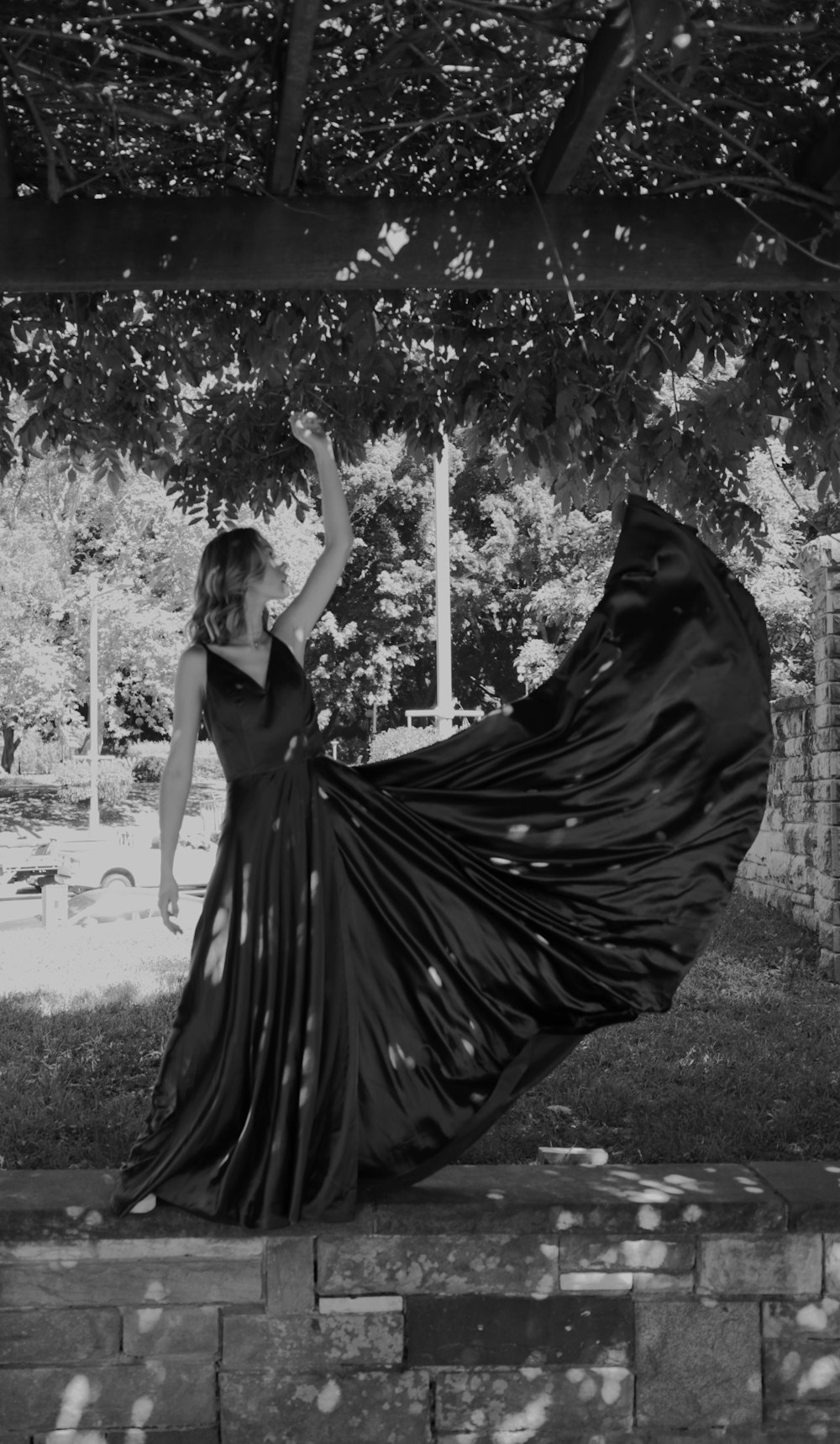 木の下に立つ長い黒いドレスを着た女性