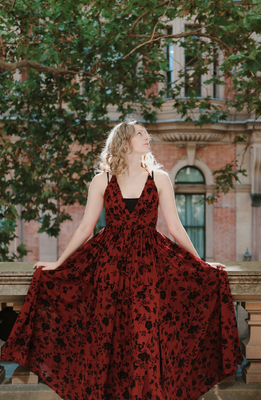 a woman in a red dress standing on a ledge