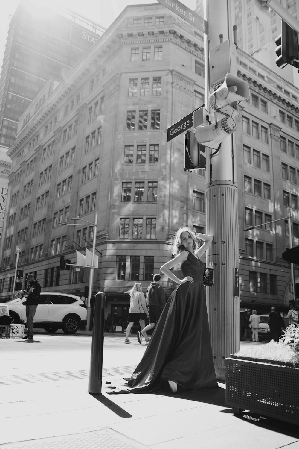 a woman in a long dress sitting on a street corner