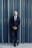 a man in a suit leaning against a wall