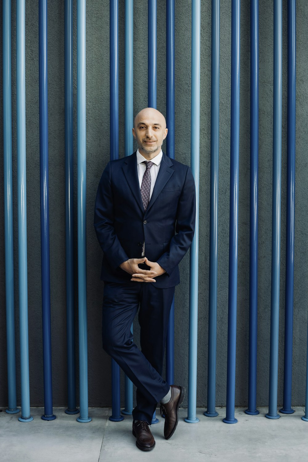 a man in a suit leaning against a wall