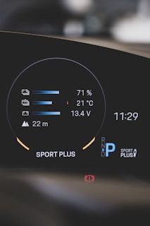 A modern car dashboard displaying various metrics such as battery level at 71%, temperature at 21°C, and voltage at 13.4V. The dashboard also shows a gear indicator with 'P' for park, the mode 'Sport Plus', a warning icon, and the time 11:29.