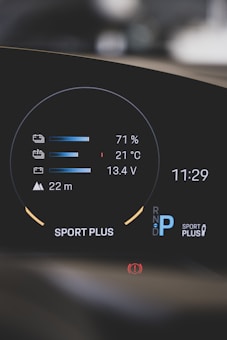 A modern car dashboard displaying various metrics such as battery level at 71%, temperature at 21°C, and voltage at 13.4V. The dashboard also shows a gear indicator with 'P' for park, the mode 'Sport Plus', a warning icon, and the time 11:29.