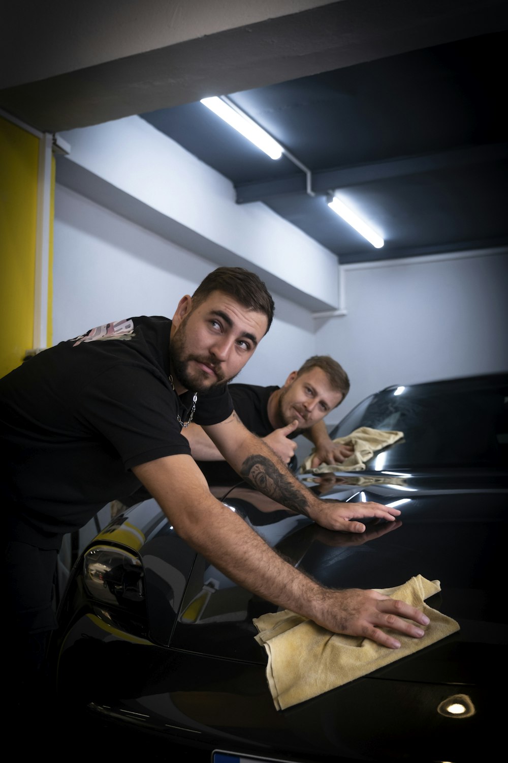 two men waxing a car in a garage
