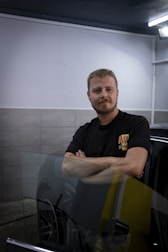 a man standing next to a car in a garage
