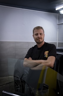 a man standing next to a car in a garage
