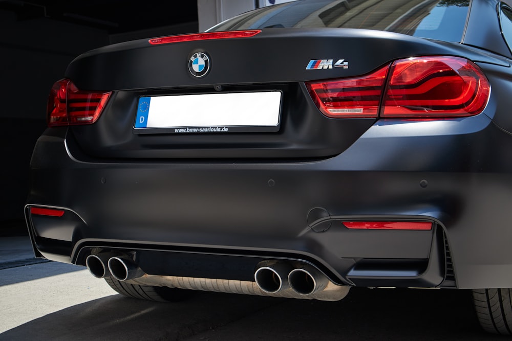 the rear end of a black car parked in a garage