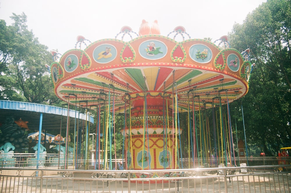 a colorful carousel in a park with trees in the background