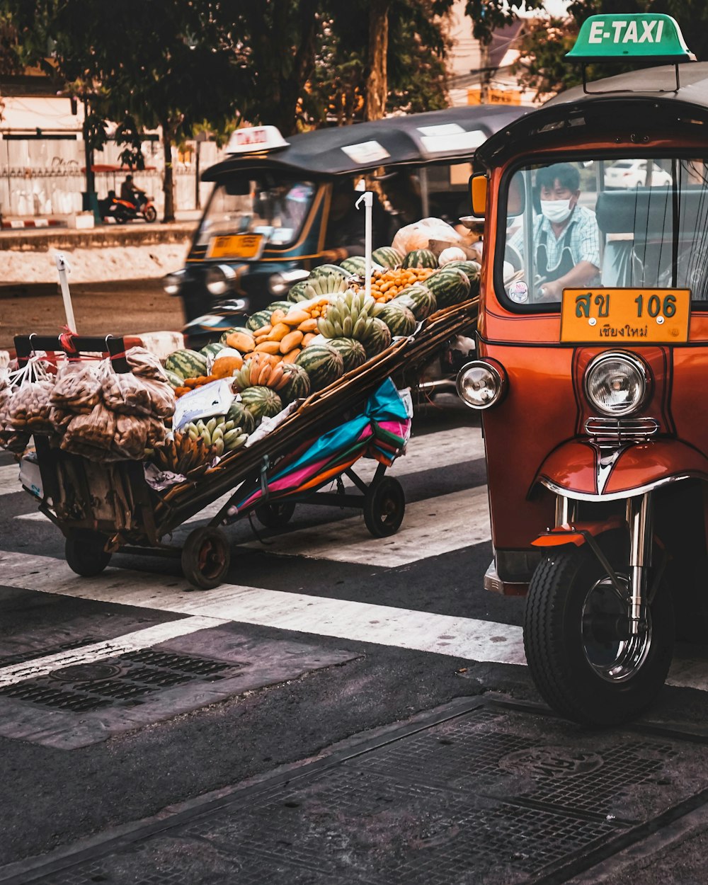 an orange truck with a cart of fruit on the back of it