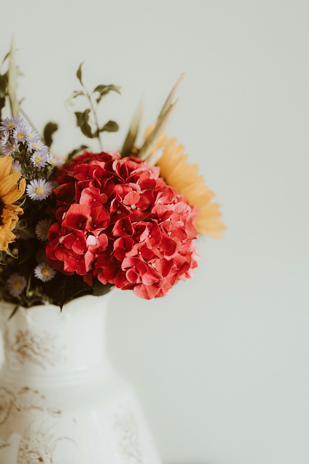 a white vase filled with lots of colorful flowers