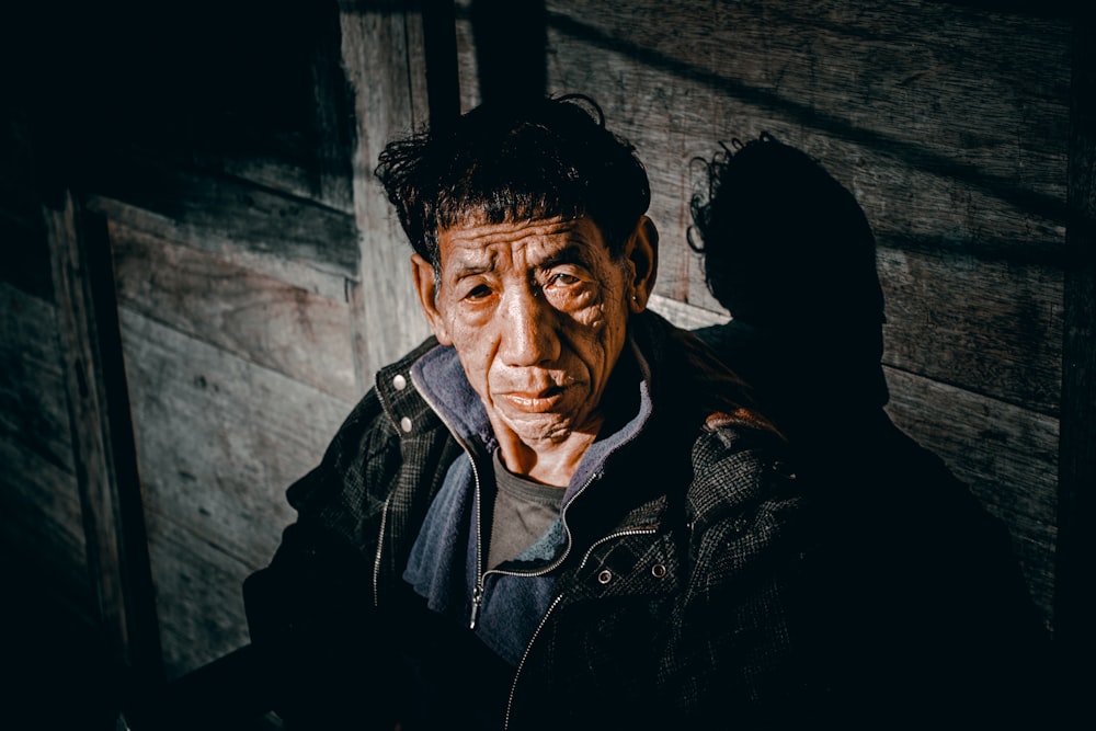 a man standing in front of a wooden wall