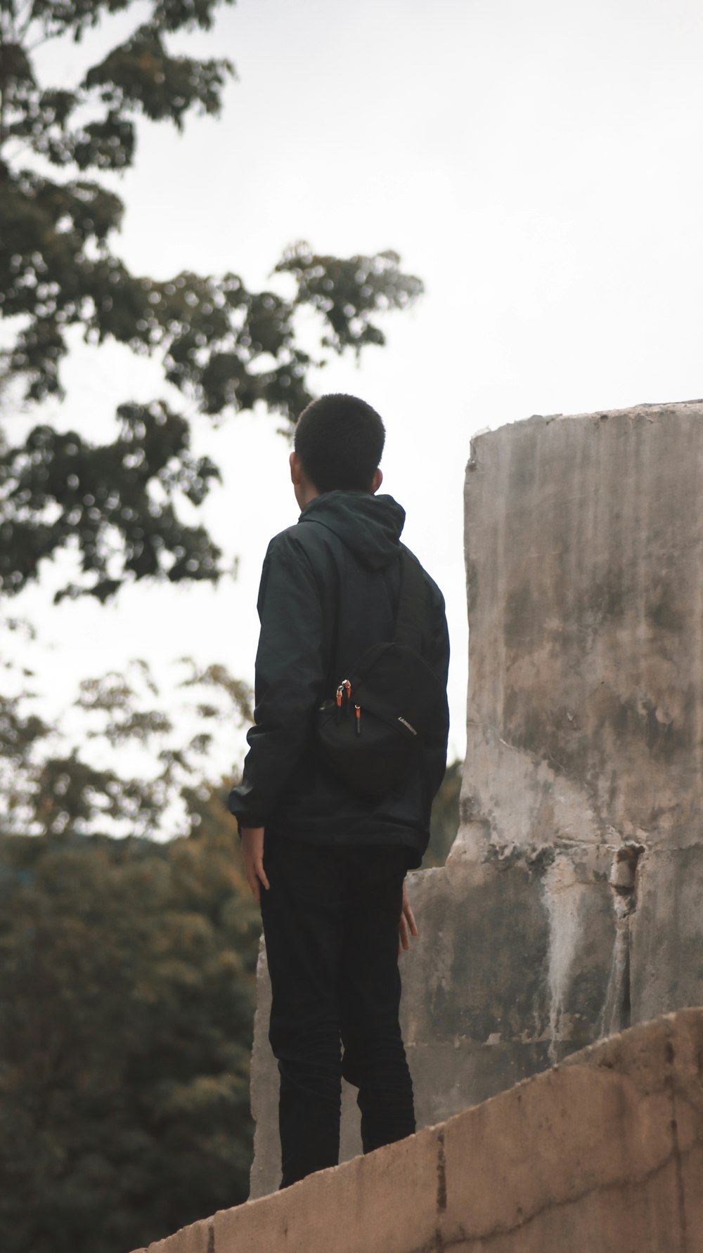 a person standing on a ledge with a backpack