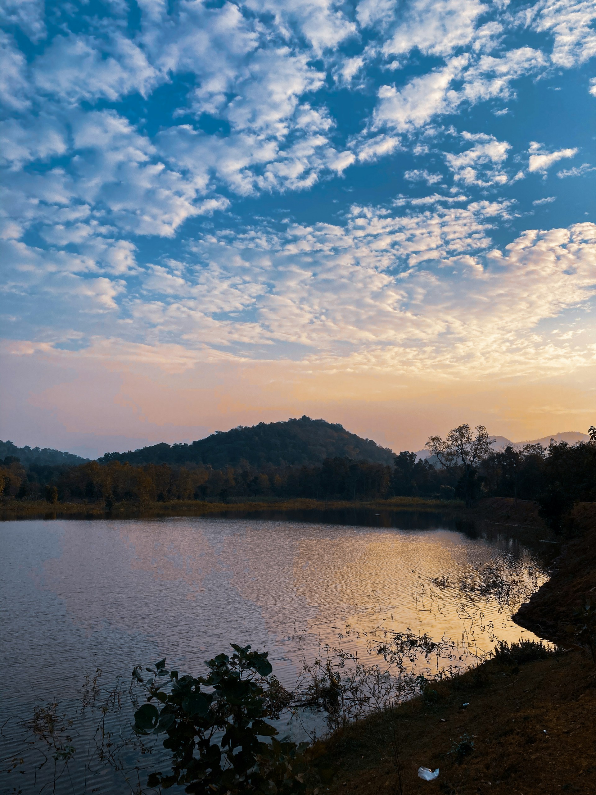 A serene landscape featuring a calm lake reflecting the soft colors of a sunset, evoking a peaceful and contemplative mood.