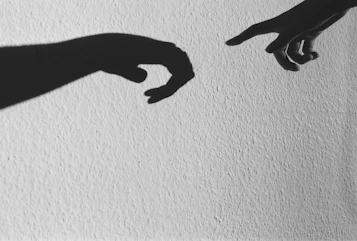 a black and white photo of two hands touching each other