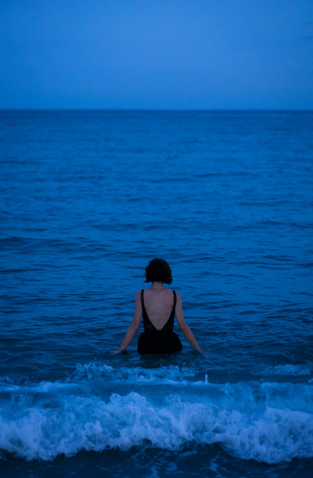 Una donna che si siede nell'oceano di notte