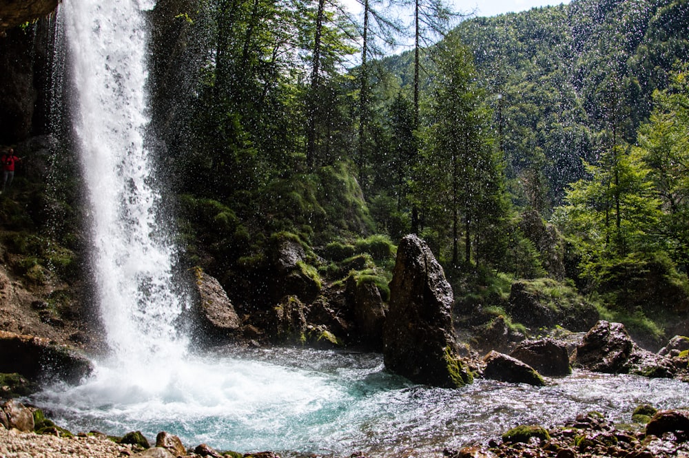 a man standing at the base of a waterfall