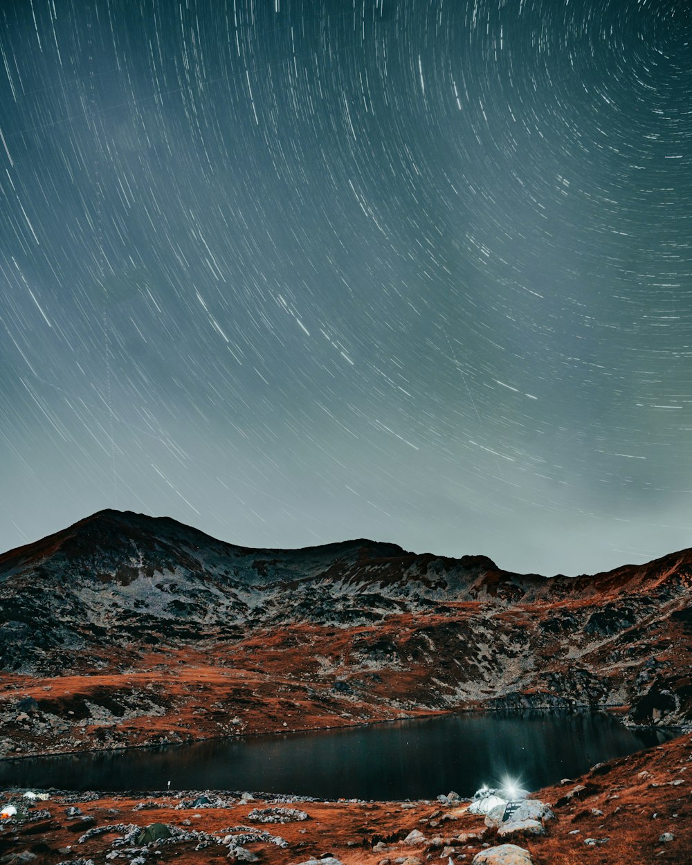 a mountain with a lake and stars in the sky