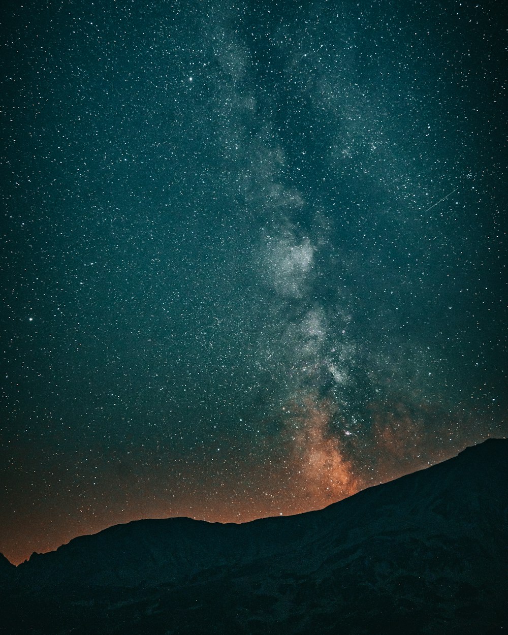 the night sky with stars above a mountain